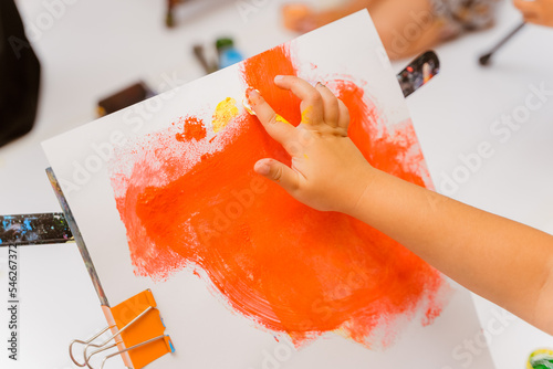 a child's hand draws with a finger on a piece of paper