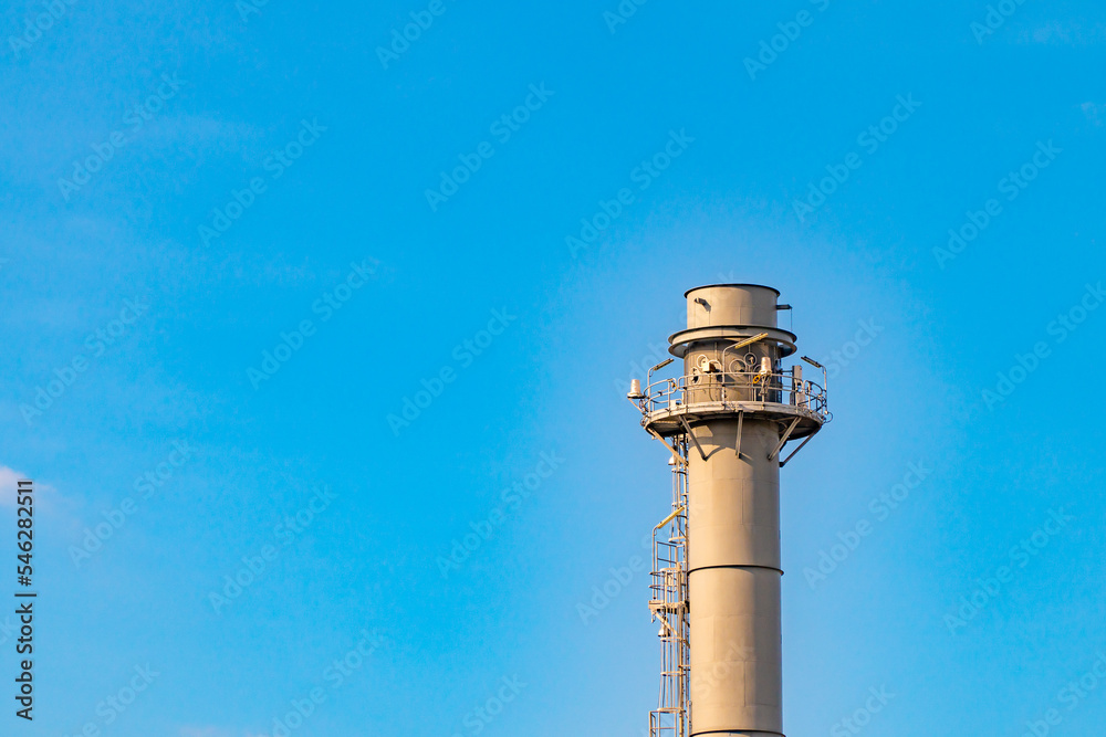 Gas flares in petroleum refinery with blue sky background Gas flares in petroleum refinery with blue sky background