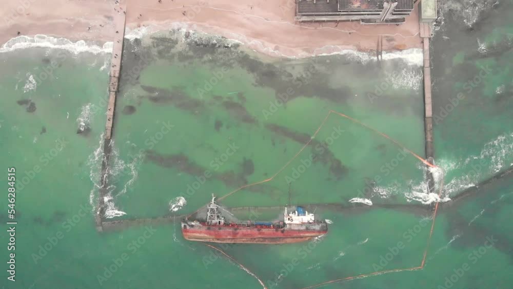 Ecological disaster. Wrecked ship near the shore in the ocean waves. Moving motion stormy sea water backrounds. Peolpe walking on the sand. Slow motion aerial video 60FPS