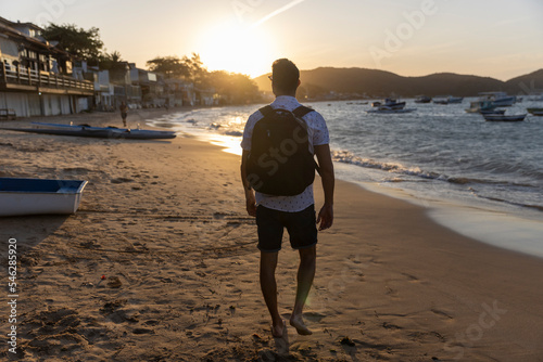 Rear view of man with backpack on beach at sunset photo