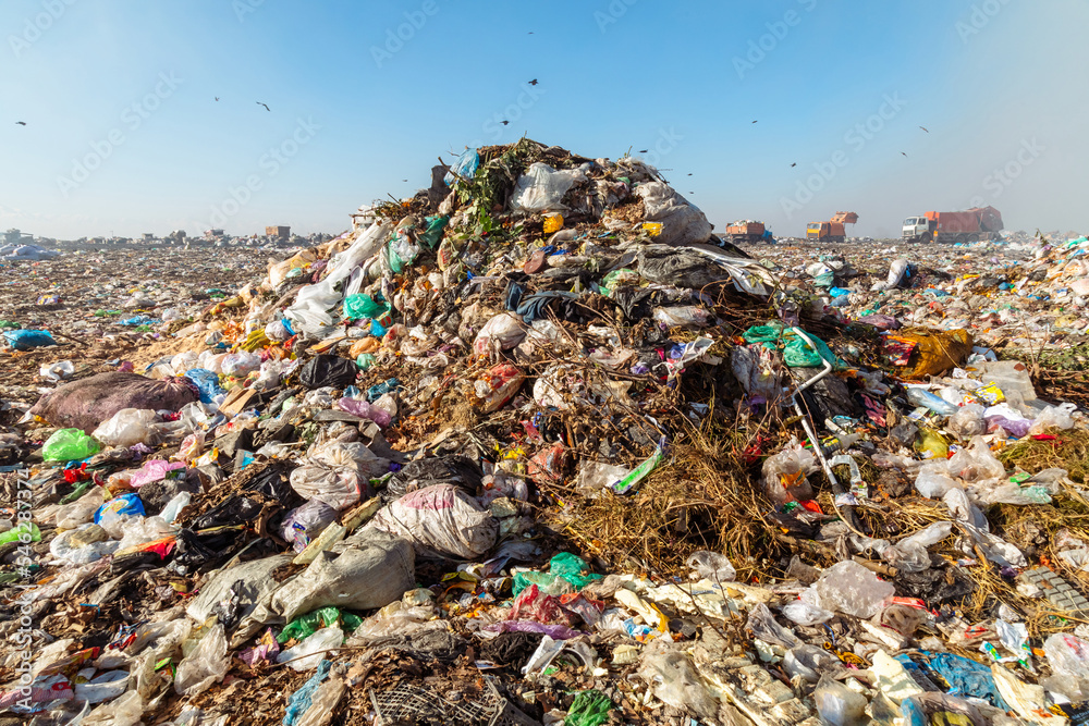 Closeup of burning trash piles in landfill with people recycling trash