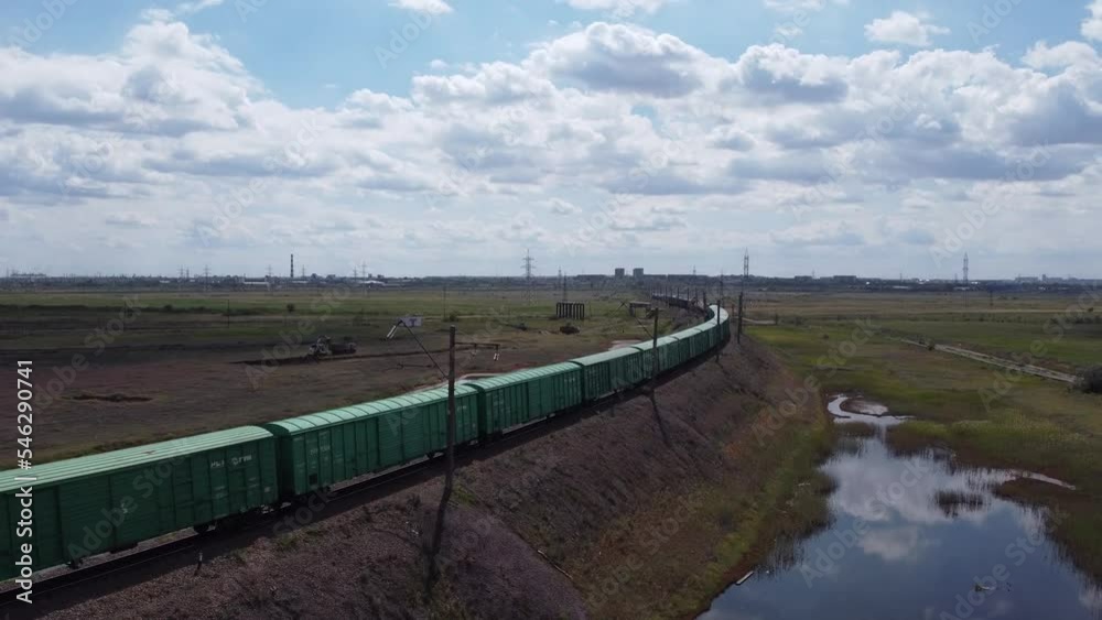 Shooting from above, a freight train is passing by. In the distance you can see the industrial area. Shooting from above, a freight train is passing by. In the distance you can see the industrial area.