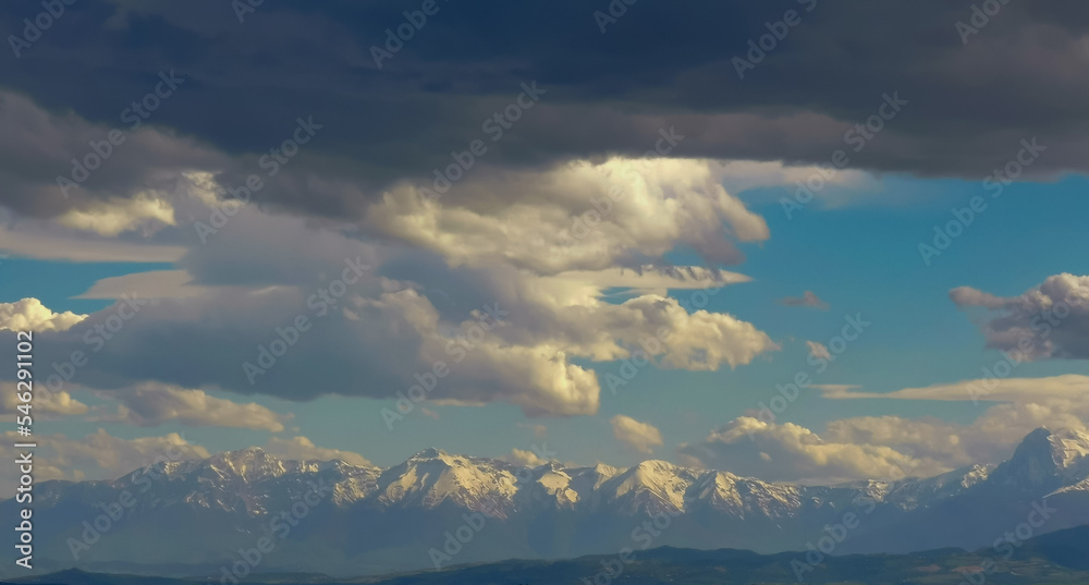 Grandi nuvole nel cielo sopra le cime innevate dei monti Appennini in una giornata di sole invernale