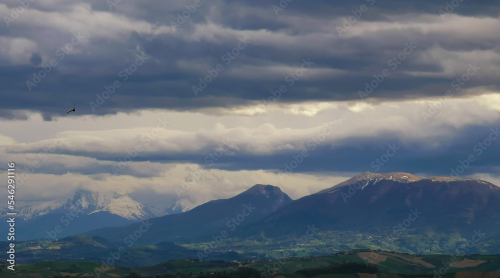 Nuvole nere e raggi di sole sopra le montagne le colline e le valli