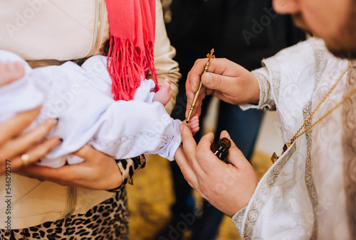 The priest in the church conducts the ceremony, the ritual of anointing the child's feet. Close-up photography, religion.