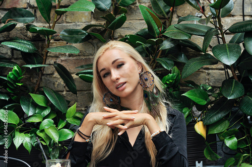 Portrait of pretty blonde girl in bohemian dreamcatcher earrings with peacock feathhemian accessories
