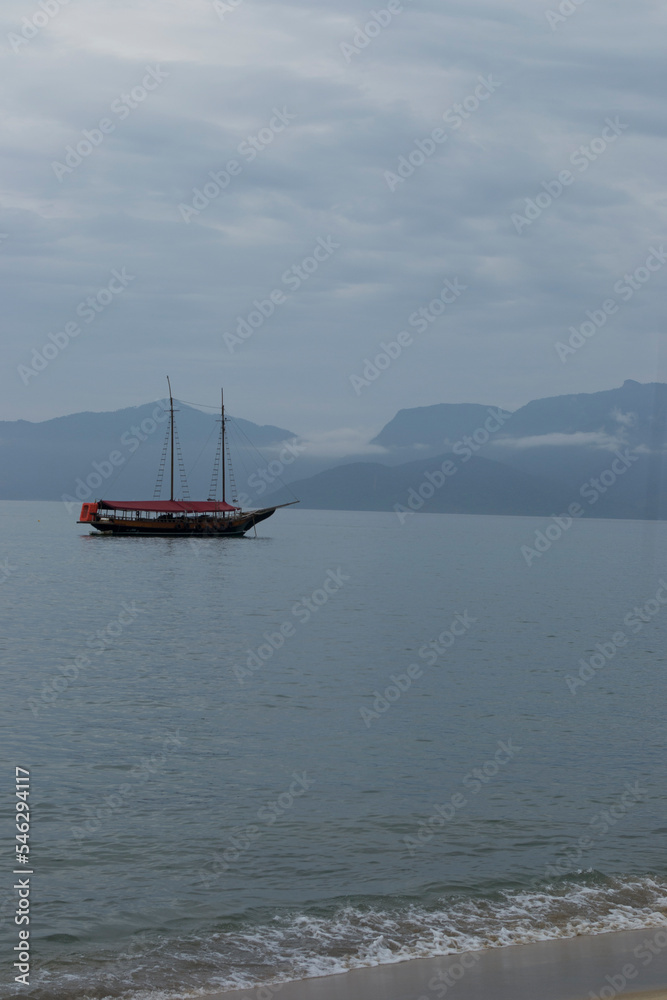 Boats in the sea of Conceição de Jacareí beach, in the background the outline of mountains and forest in Rio de Janeiro, Brazil. Boats in the sea of Conceição de Jacareí beach, in the background the outline of mountains and forest in Rio de Janeiro, Brazil.