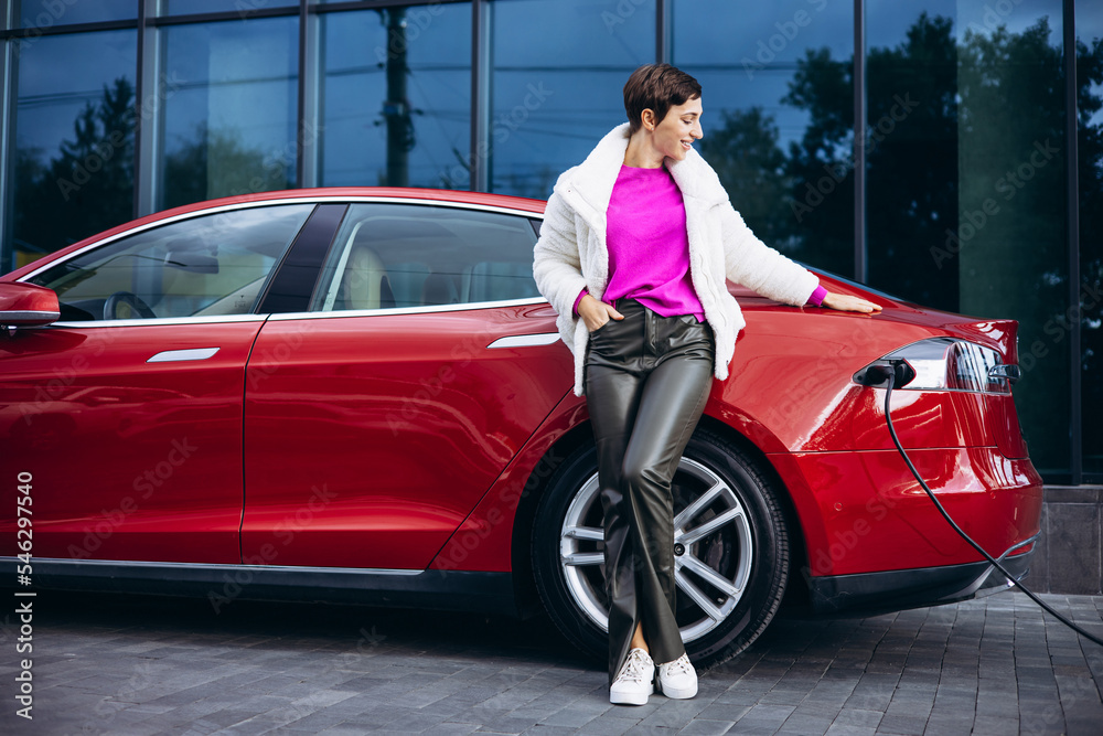 Woman charging electric car by the office building Woman charging electric car by the office building