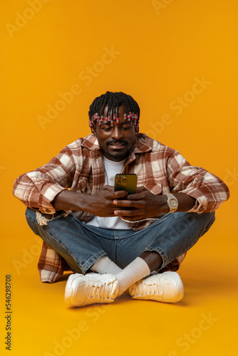 Young african man using smartphone over isolated yellow background