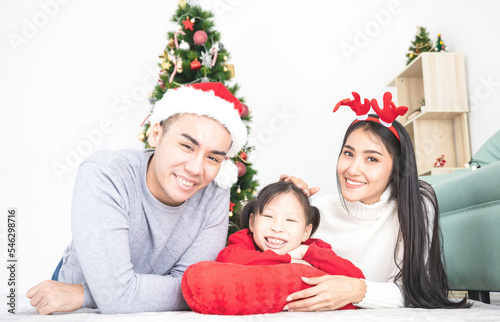 Asian family lying together in front of Christmas tree in white room