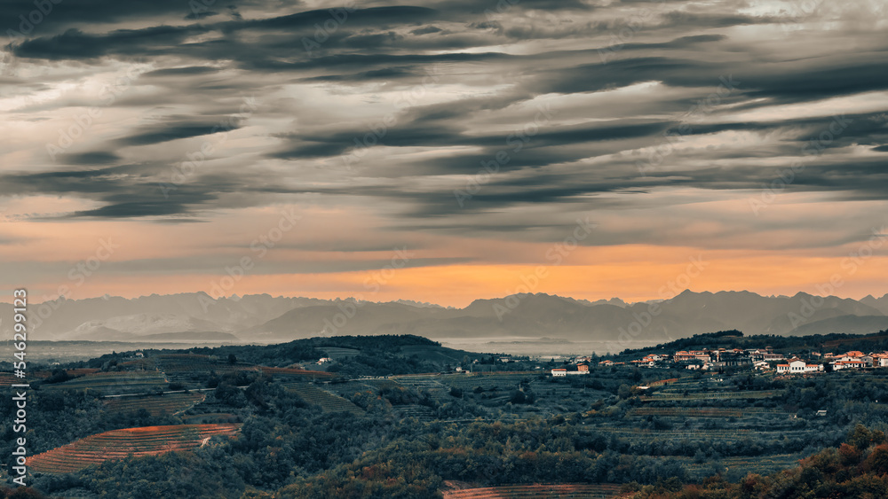 Scenic landscape at Šmartno, Brda Goriska, Slovenia. Vineyards with mountain chain in background under a dramatic sky.