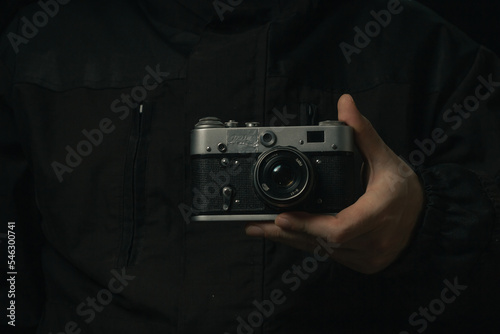 man holding Retro film photo camera isolated on black background soviet