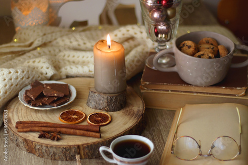 Cup of tea or coffee  various sweets and spices  Christmas decorations  comfy blanket  books and glasses. Selective focus.