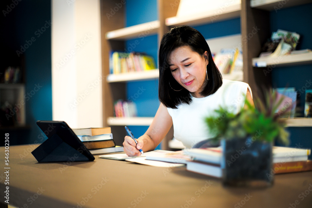 Portrait beautiful Asian woman works at the home office with blurred shelf of books in background Portrait beautiful Asian woman works at the home office with blurred shelf of books in background
