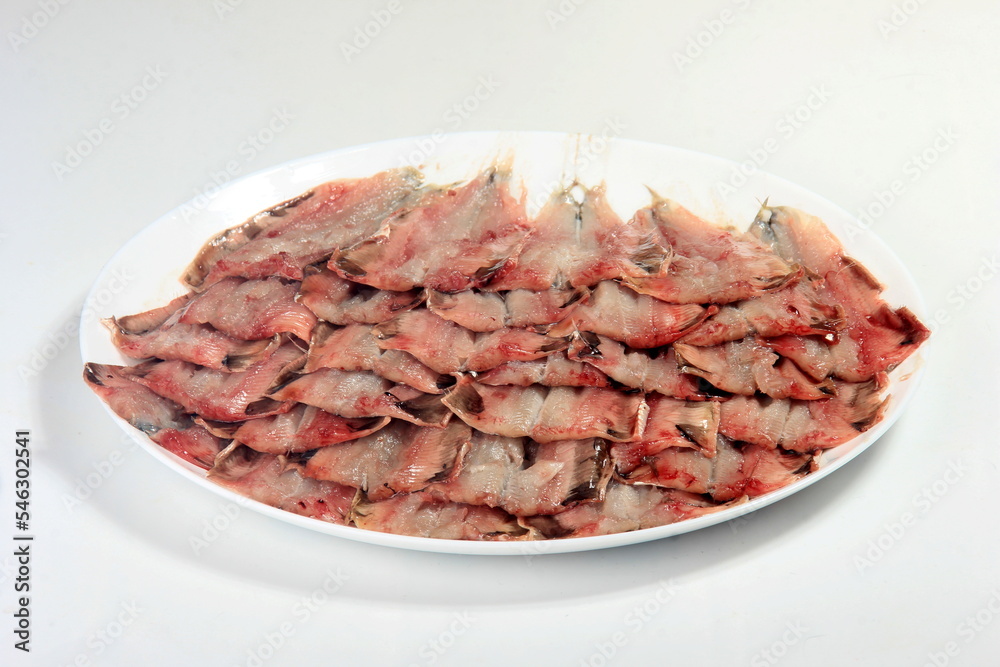 many opened and cleaned small fish on a plate on a white background