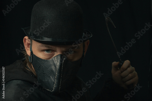 Scary man with sickle or hook creepy mask and hat in the dark photo