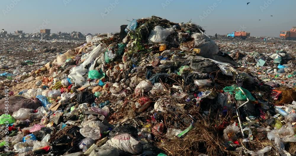 Closeup of burning trash piles in landfill with people recycling trash