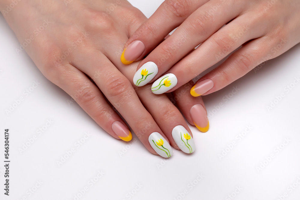 Yellow white manicure with painted colors on long oval nails close-up on a white background Yellow white manicure with painted colors on long oval nails close-up on a white background