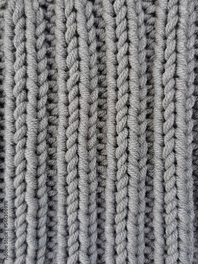 Gray knitted texture. Elastic knitting pattern close up. Needlework hobbies. 