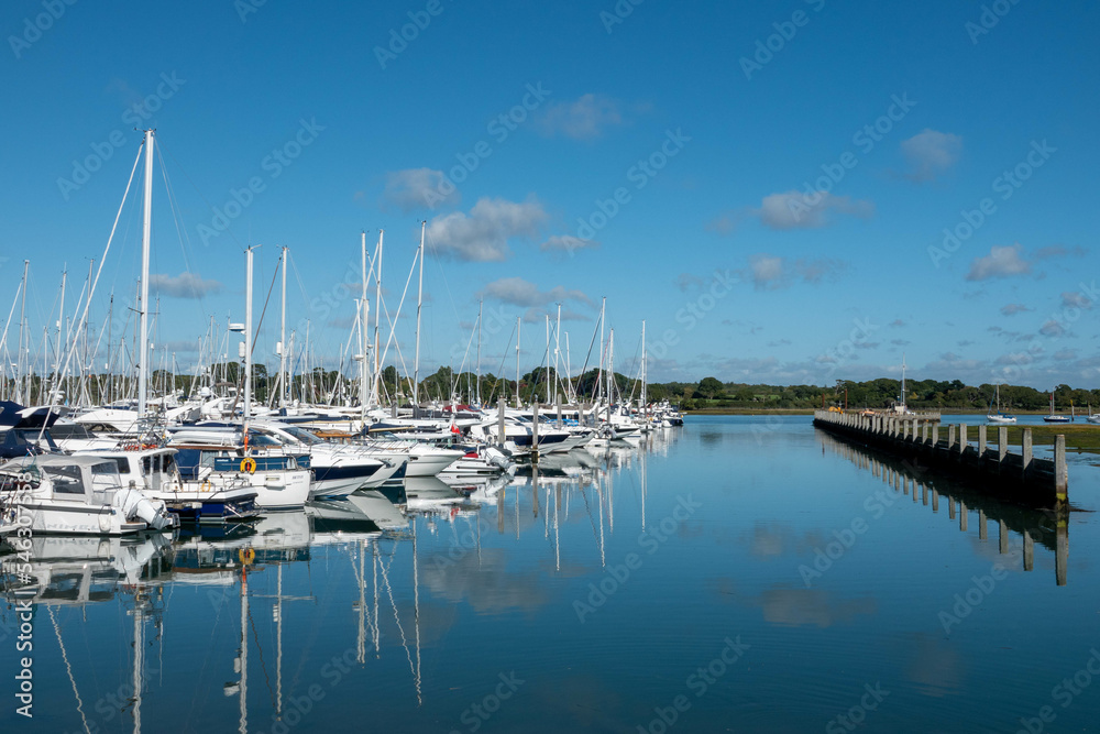 boats in the marina at Lymington Hampshire with blue sky and clear reflections in the water