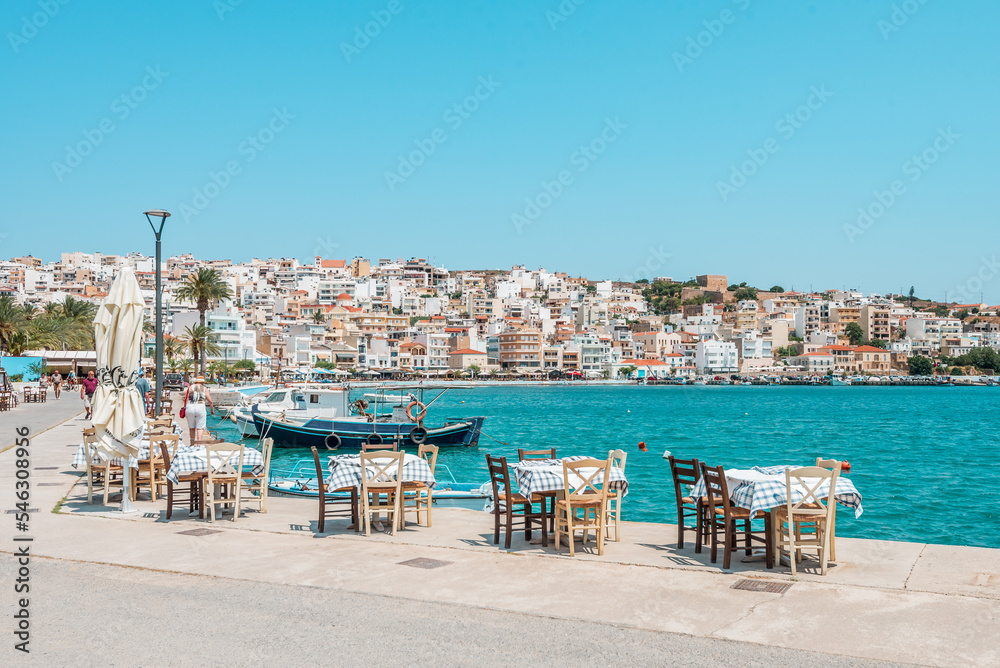 sitia, crete island, greece: waterfront pier with taverna tables and fishermen boats