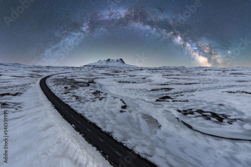 Long asphalt road surrounded with snow and ice at night in Iceland