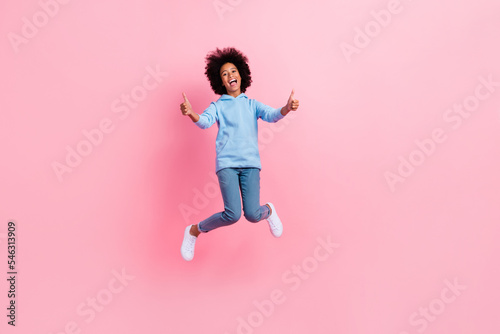 Full length portrait of excited crazy person jumping demonstrate thumbs up feedback isolated on pink color background