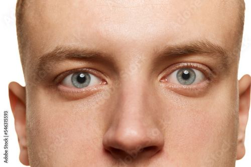 Close-up portrait of male grey eyes looking straight isolated over white studio background. Concept of men's health, vision,