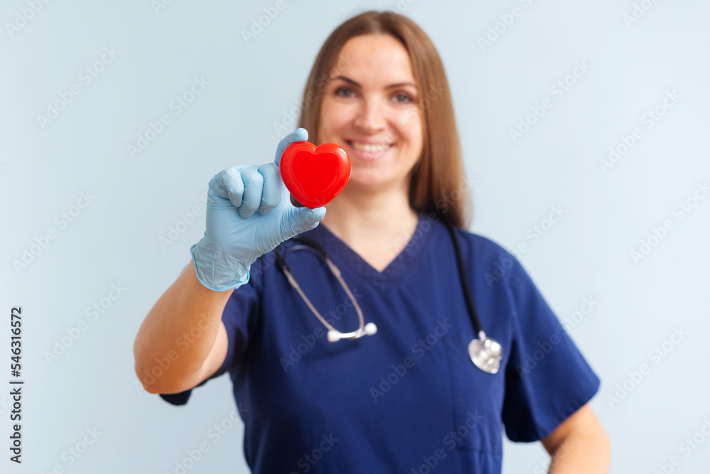 Female doctor with stethoscope holding red heart on blue background Female doctor with stethoscope holding red heart on blue background