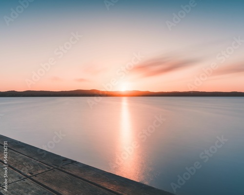 Scenic shot of the pink sunset reflecting the last rays over the still water © Daniel Remo/Wirestock Creators
