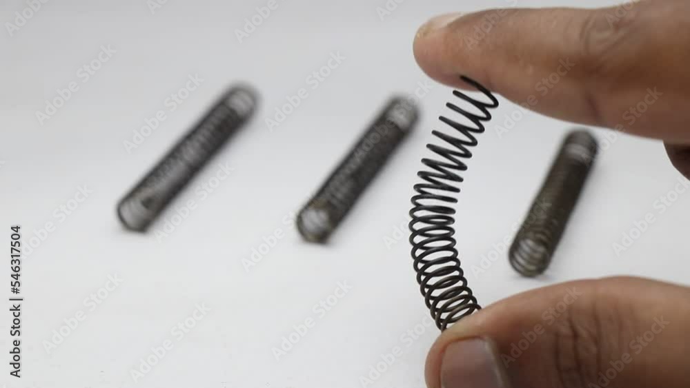 Bending a metal coil spring to test its flexibility. Spare metal springs small in size