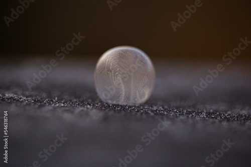 Closeup of the frozen water drop on the grey surface, suitable for backgrounds