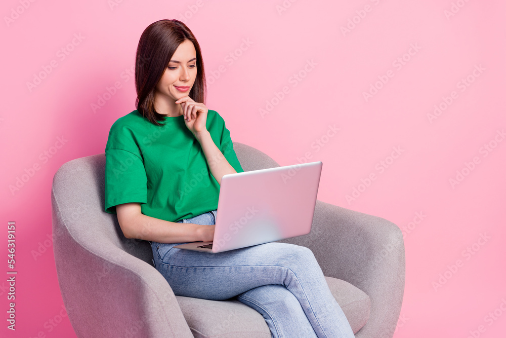Portrait of creative minded lady sit chair hand touch chin use netbook isolated on pink color background Portrait of creative minded lady sit chair hand touch chin use netbook isolated on pink color background