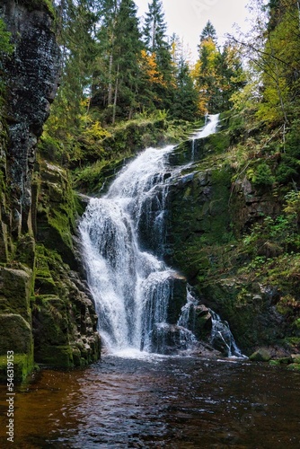 Vertical shot of a waterfall flowing down from mossy cliffs