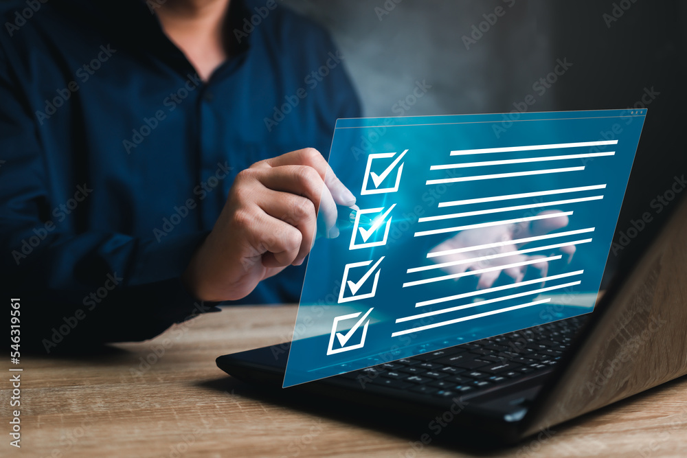 Business concept and smart checklist on virtual screen,A man use a pen marking about exploring the topics on the digital form check sheet and use a laptop working in a modern office - obrazy, fototapety, plakaty 