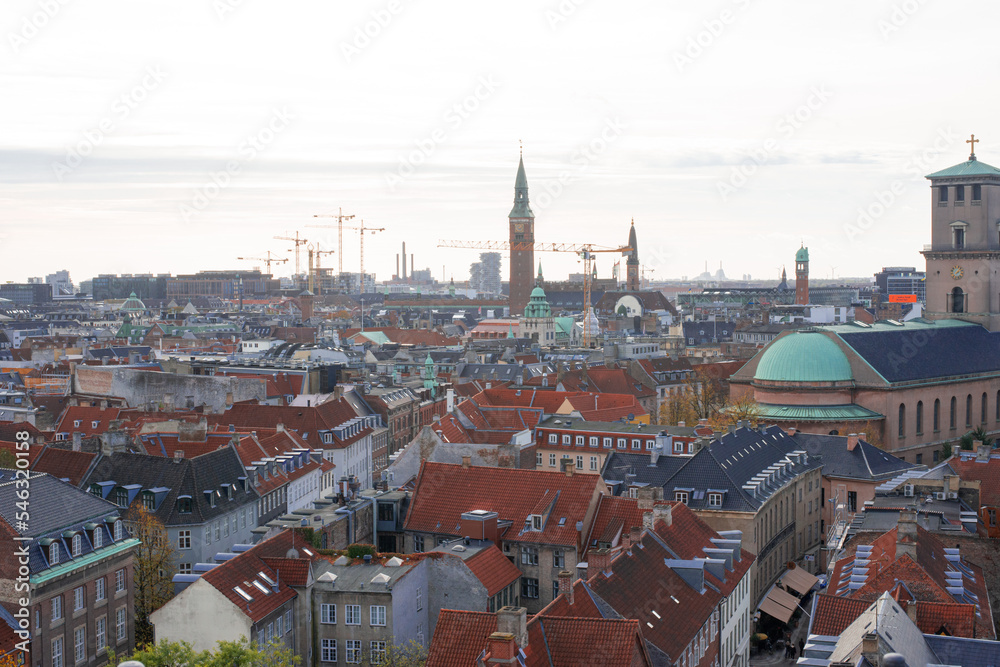 construction cranes on the horizon above tiled roofs of historical center of Copenhagen