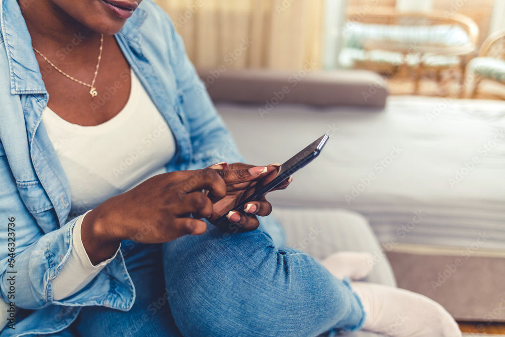 Shot of a young woman using a smartphone on the sofa at home. Cropped shot of an attractive young woman using her cellphone while sitting in the living room during the day.