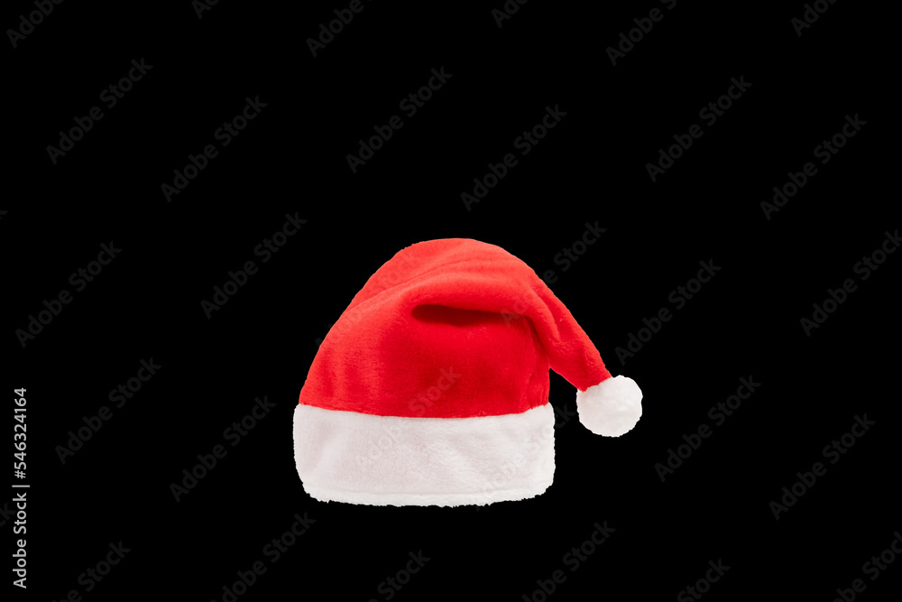 Red and white christmas hat in black background. Santa claus cap on the plain dark background. Red and white christmas hat in black background. Santa claus cap on the plain dark background.