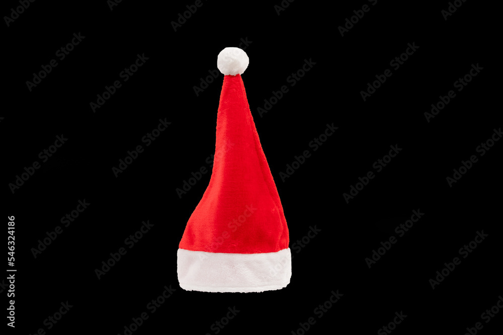Red and white christmas hat in black background. Santa claus cap on the plain dark background. Red and white christmas hat in black background. Santa claus cap on the plain dark background.