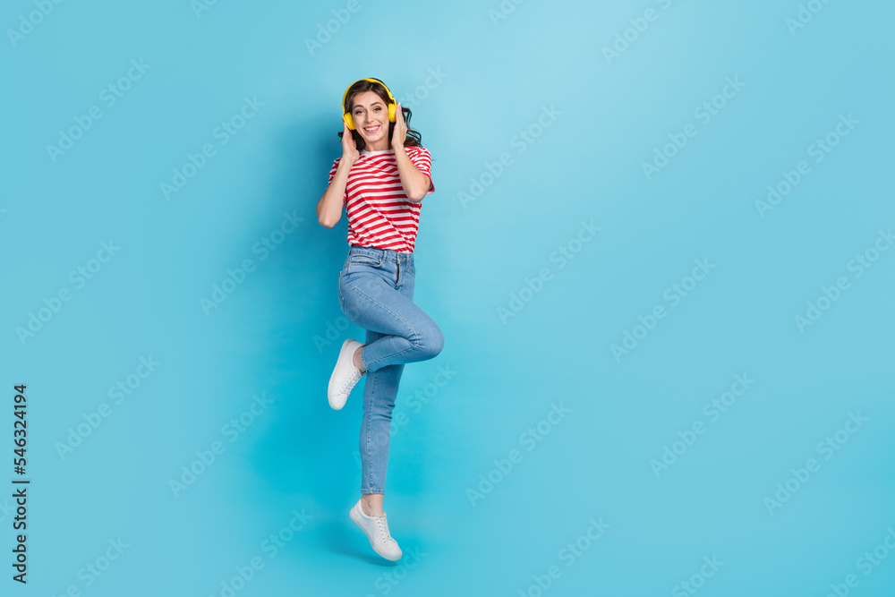 Full length photo of pretty funky girl dressed red t-shirt arms headphones empty space isolated blue color background Full length photo of pretty funky girl dressed red t-shirt arms headphones empty space isolated blue color background