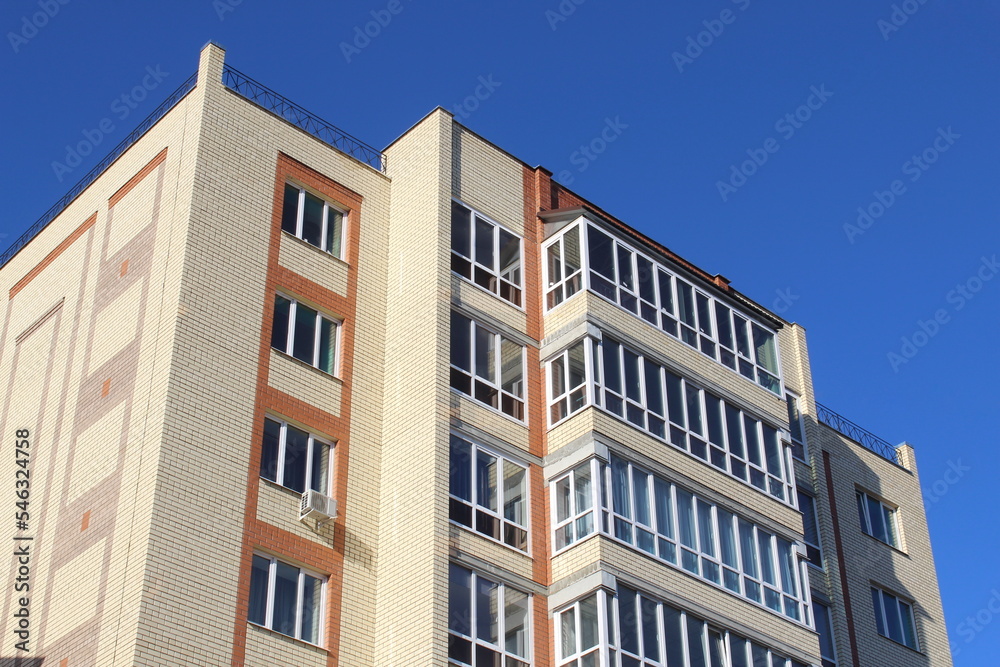 Multi-storey building with balconies against the sky on a sunny day.