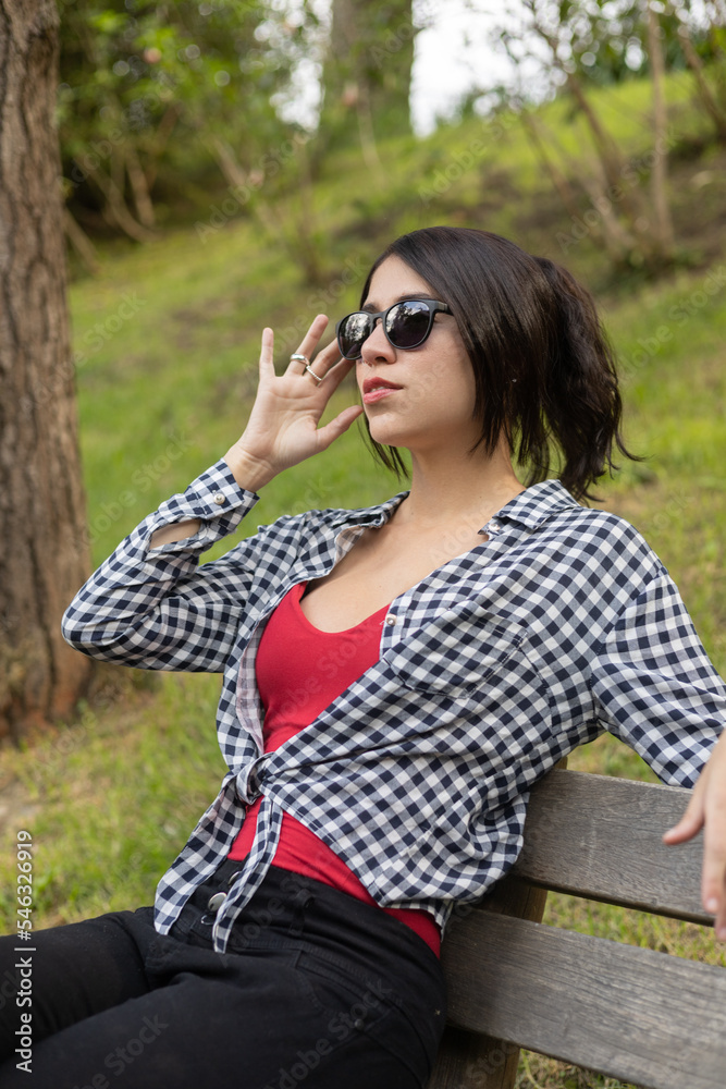 sitting young latin woman with black hair in a ponytail and sunglasses on a sunny day, lifestyle, beauty and fashion, face details sitting young latin woman with black hair in a ponytail and sunglasses on a sunny day, lifestyle, beauty and fashion, face details