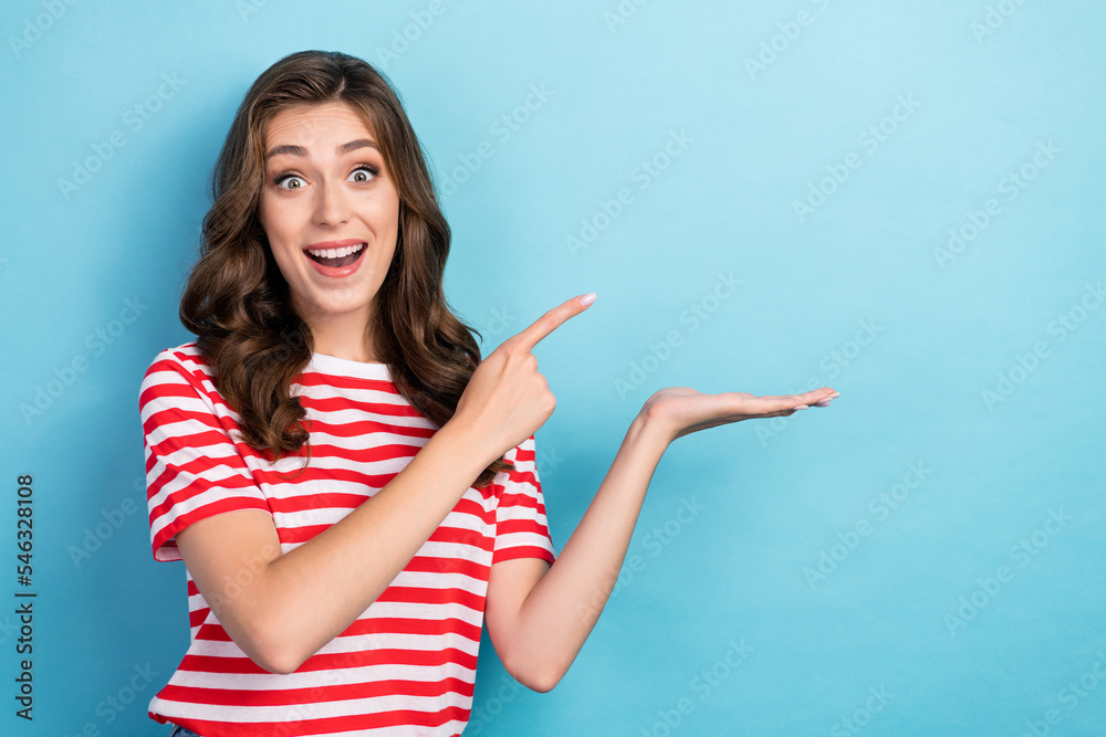 Photo of positive cheerful lady wear stylish clothes arm demonstrate empty space shopping sale isolated on blue color background Photo of positive cheerful lady wear stylish clothes arm demonstrate empty space shopping sale isolated on blue color background