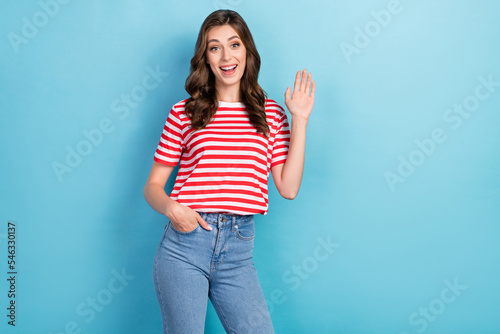 Photo of cute joyful lady wear fashionable clothes raise arm glad see meet you say hello empty space isolated on blue color background