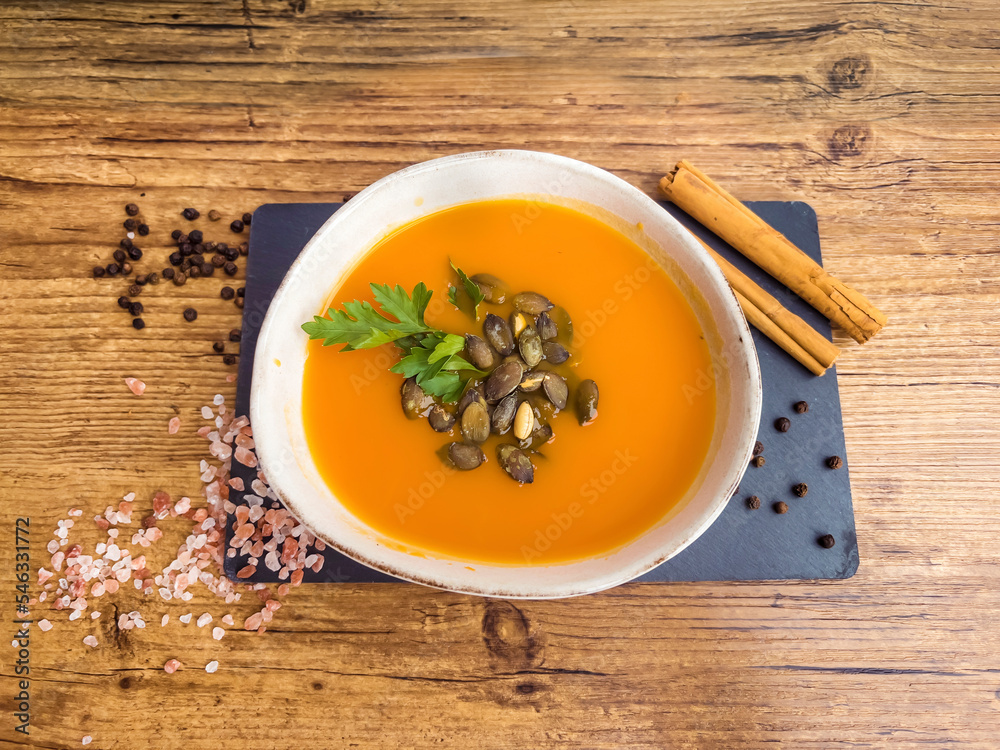 Pumpkin traditional soup with creamy  texture on gray textured background . Top view 