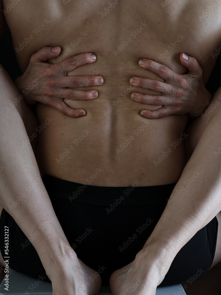 A man and a woman in each other's arms. Women's legs and arms embrace a strong muscular male back. Naked bodies. Photo without a face.
