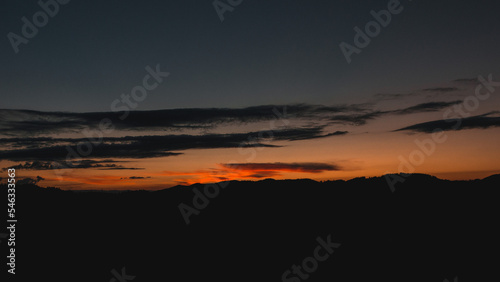Sky after sunset with mountains as silhouette. silhouette of the black forest mountains after sunset with a few clouds in the summer. idyllic natural scene