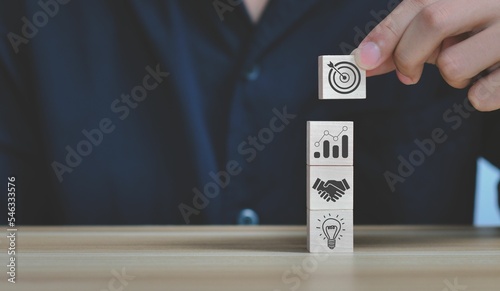Man's hand holding wooden cubes with business strategy-related icons on them