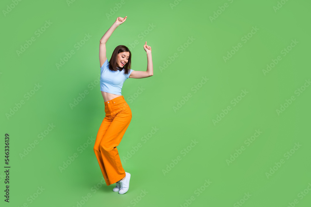 Full length portrait of pretty positive person enjoy dancing empty space isolated on green color background Full length portrait of pretty positive person enjoy dancing empty space isolated on green color background