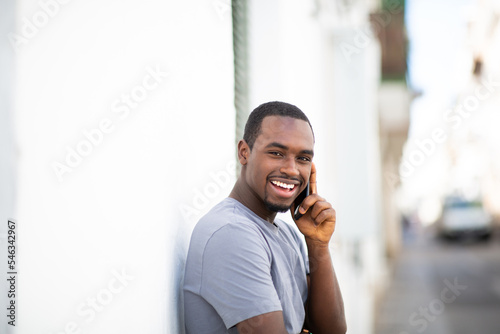 Happy young black man talking on mobile phone outside